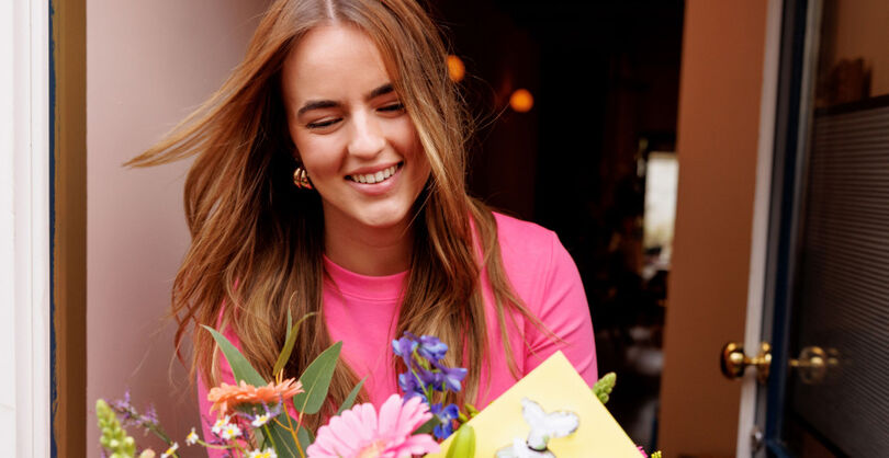 Vrouw ontvangt bloemen met een kaart
