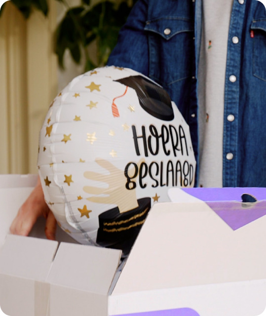 Een ballon die uit een doos vliegt met de tekst 'hoera geslaagd'