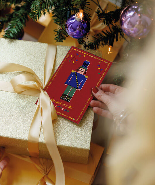 Een kaart van Kinderpostzegels op een cadeautje onder de kerstboom
