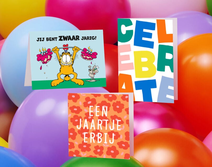 verschillende verjaardagskaarten gestapeld tussen een achtergrond van ballonnen