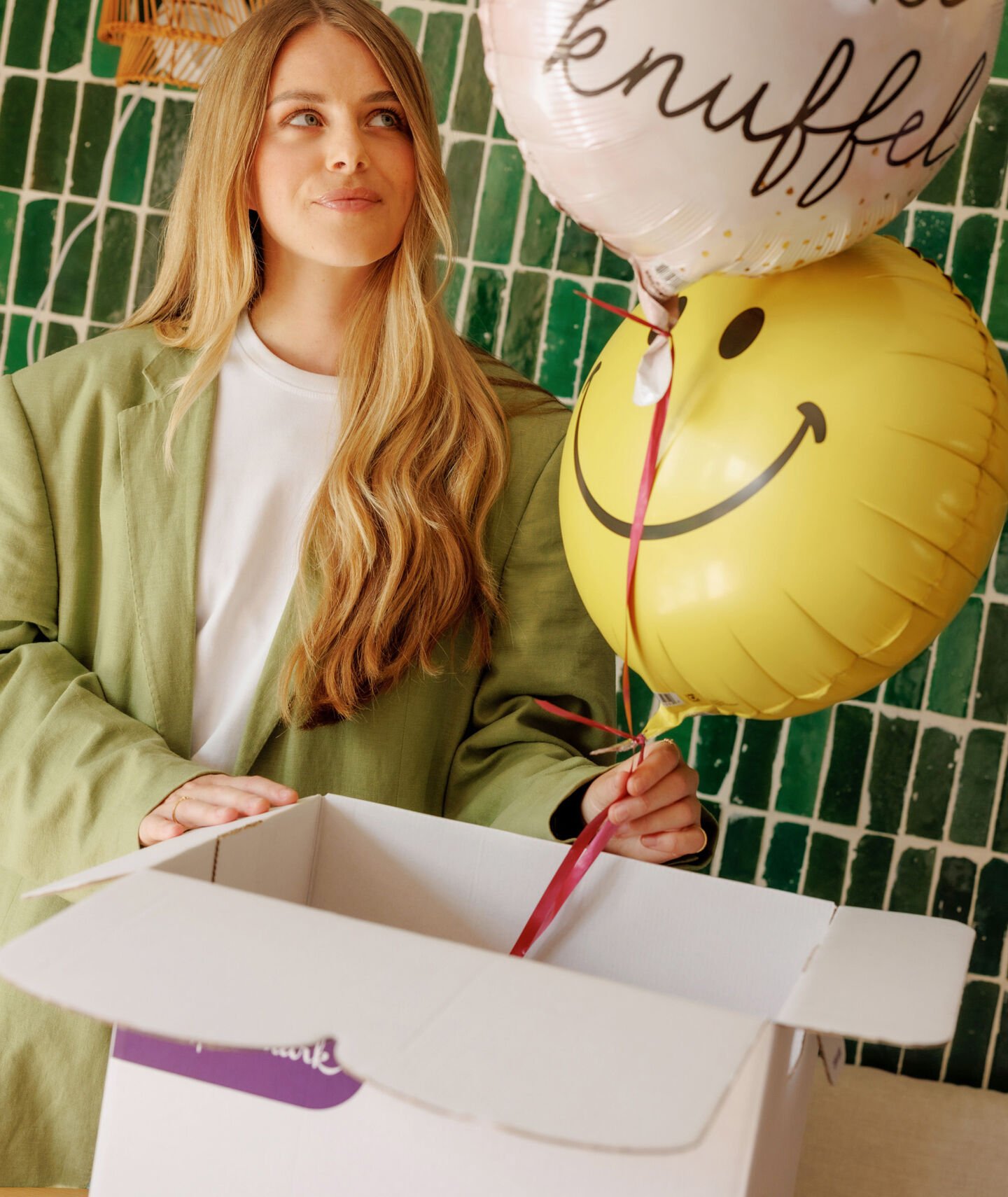 Vrouw houdt 2 beterschapshelium ballonnen vast die uit een doos komen te vliegen