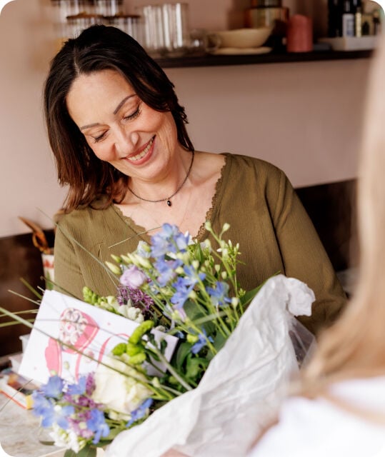 Een vrouw met een bos bloemen in haar handen