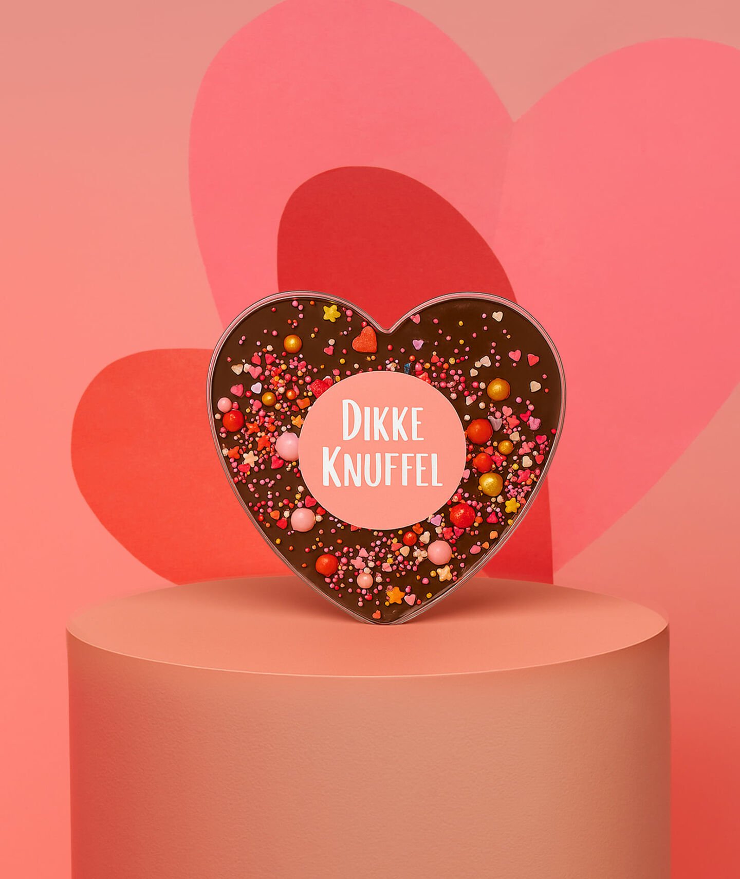Een chocoladehart met de tekst 'dikke knuffel' tegen een rode hartjesachtergrond
